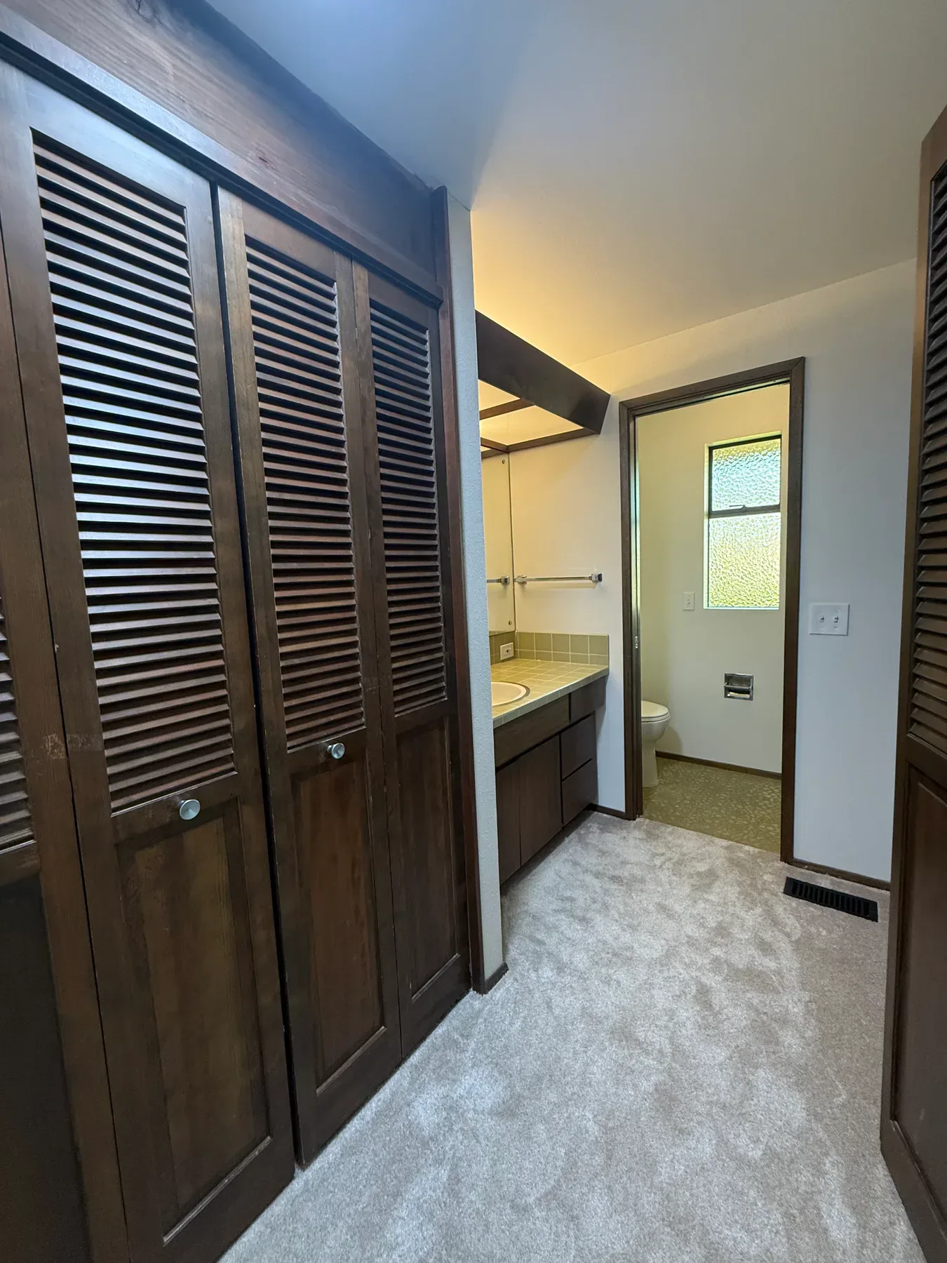 Original primary suite vanity with dark louvered closets in Bellevue, WA