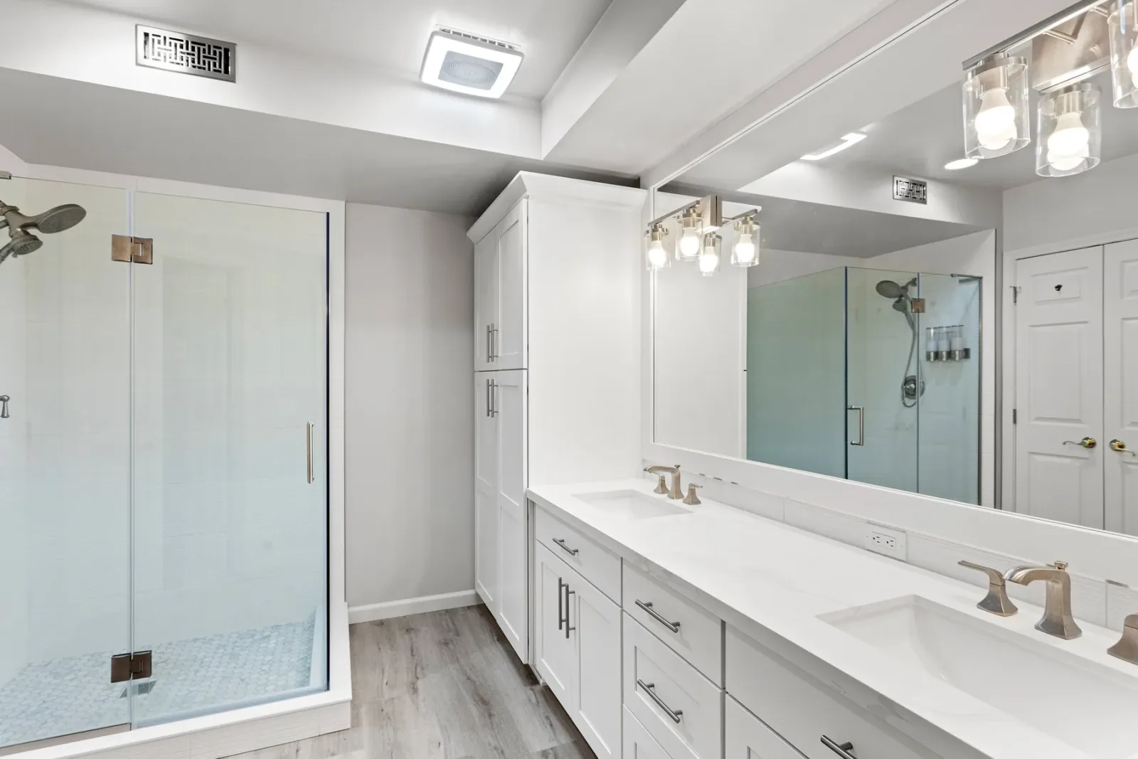 Bright Bellevue bathroom with double vanity, linen storage, and frameless glass shower