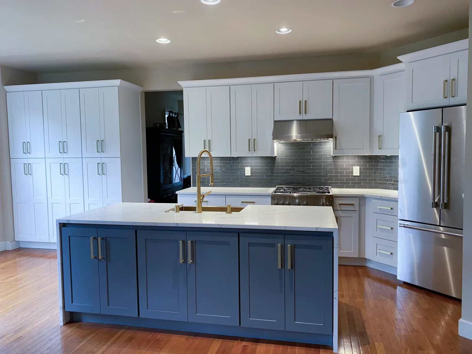Finished Issaquah kitchen with blue island, white cabinetry, and gold hardware