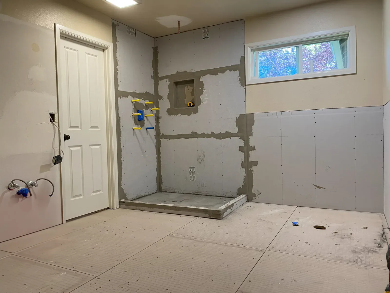 Shower area under construction with cement backer board and roughed-in plumbing in Issaquah, WA