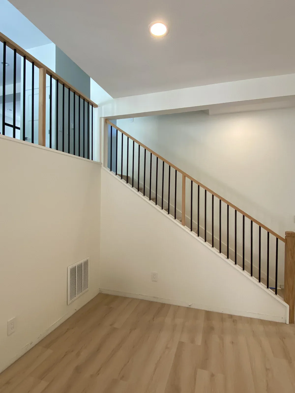 Open staircase with an oak handrail and black metal balusters after the Kirkland remodel