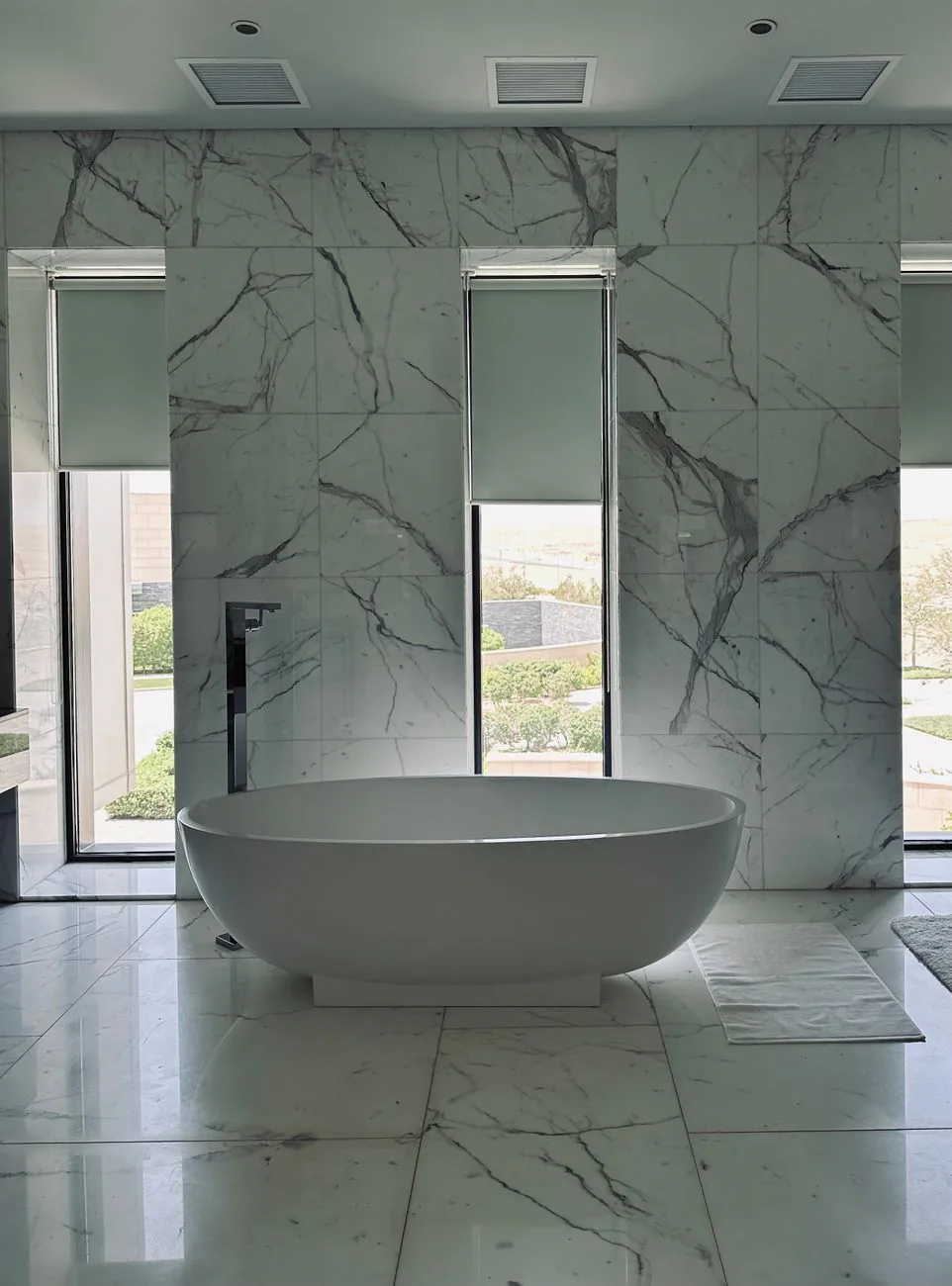 Completed Kirkland primary bathroom with marble finishes and freestanding soaking tub