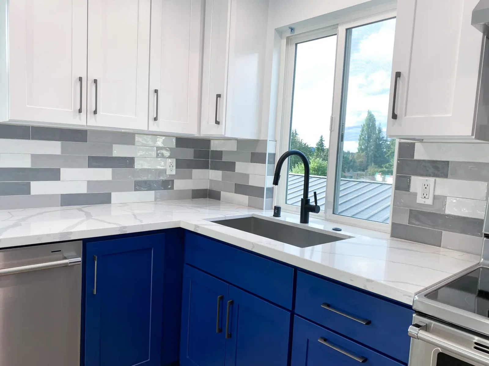 Sink wall with blue base cabinets and white countertops