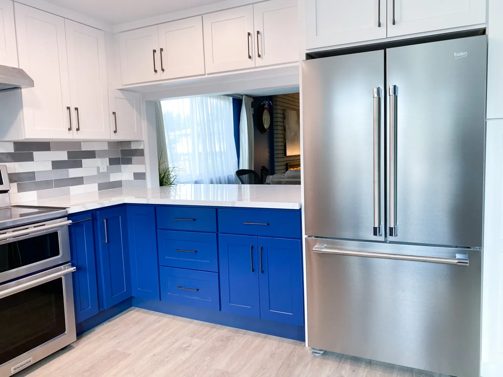 Two-tone cabinetry and stainless refrigerator in the finished kitchen